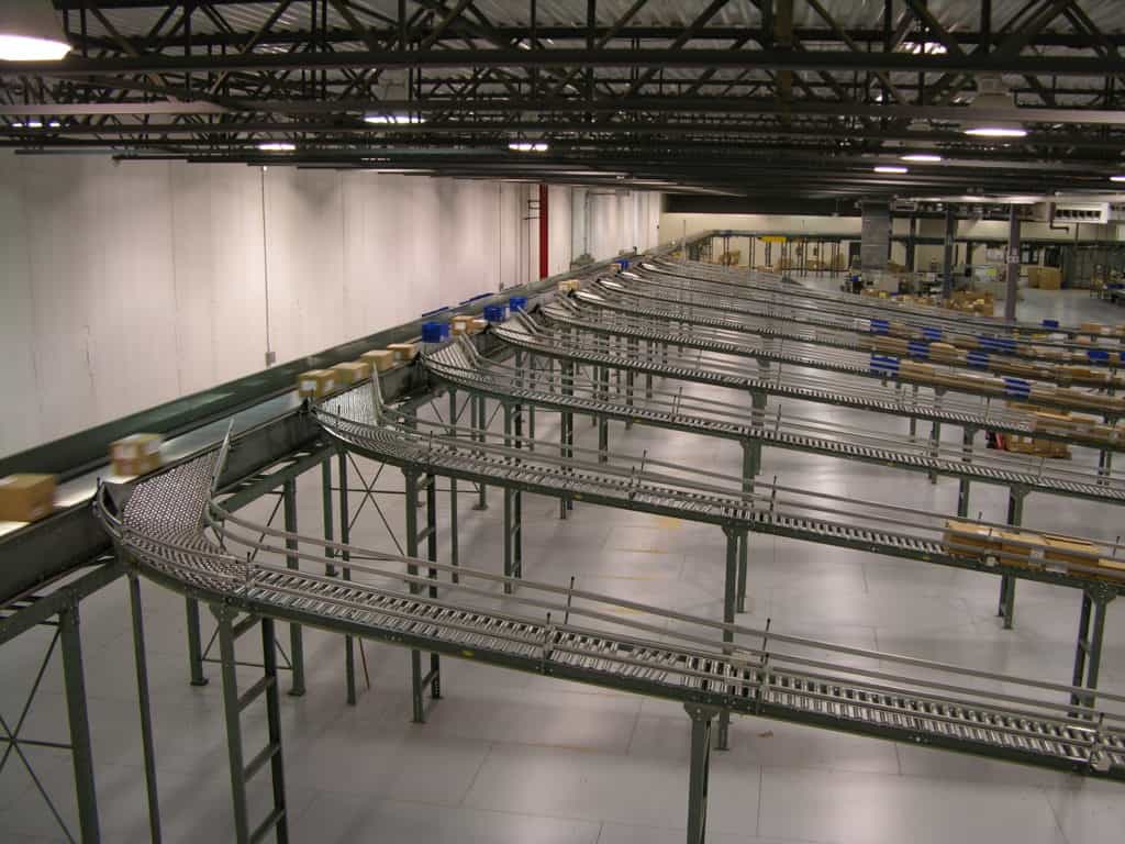 Accumulation Conveyor: Zero-Pressure vs. Minimum-Pressure, and How to Choose 3 Rows of gravity roller conveyor lanes running down from an overhead sorter at the Barnes & Noble distribution center