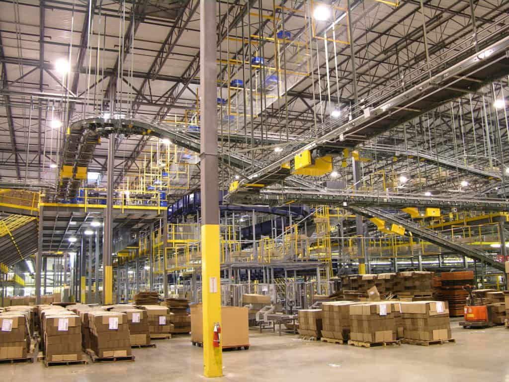 Types of Pallet Racking: Selective, Drive-In, Push-Back, Pallet Flow, and When Each Fits 2 Palletized cartons staged on the floor beneath elevated conveyor and yellow mezzanine walkways in the Barnes & Noble distribution center, where Century Conveyor integrated the conveyor system