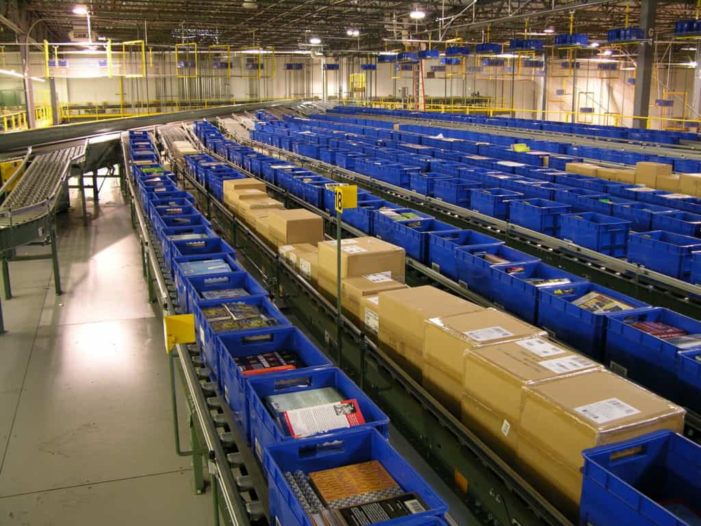 Accumulation Conveyor: Zero-Pressure vs. Minimum-Pressure, and How to Choose 1 Blue totes and tan cartons queued on parallel accumulation conveyor lanes in a Barnes & Noble distribution center