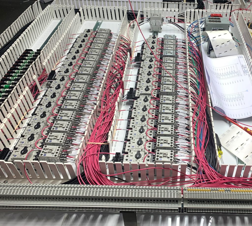 One Family, Many Solutions: Inside the LEI Solution Network 1 Control panel under fabrication with rows of terminal blocks and relays wired in red and white